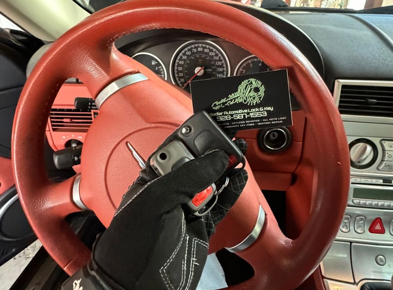 Close-up of a Chrysler Crossfire car key and fob on a workshop table, ready for programming